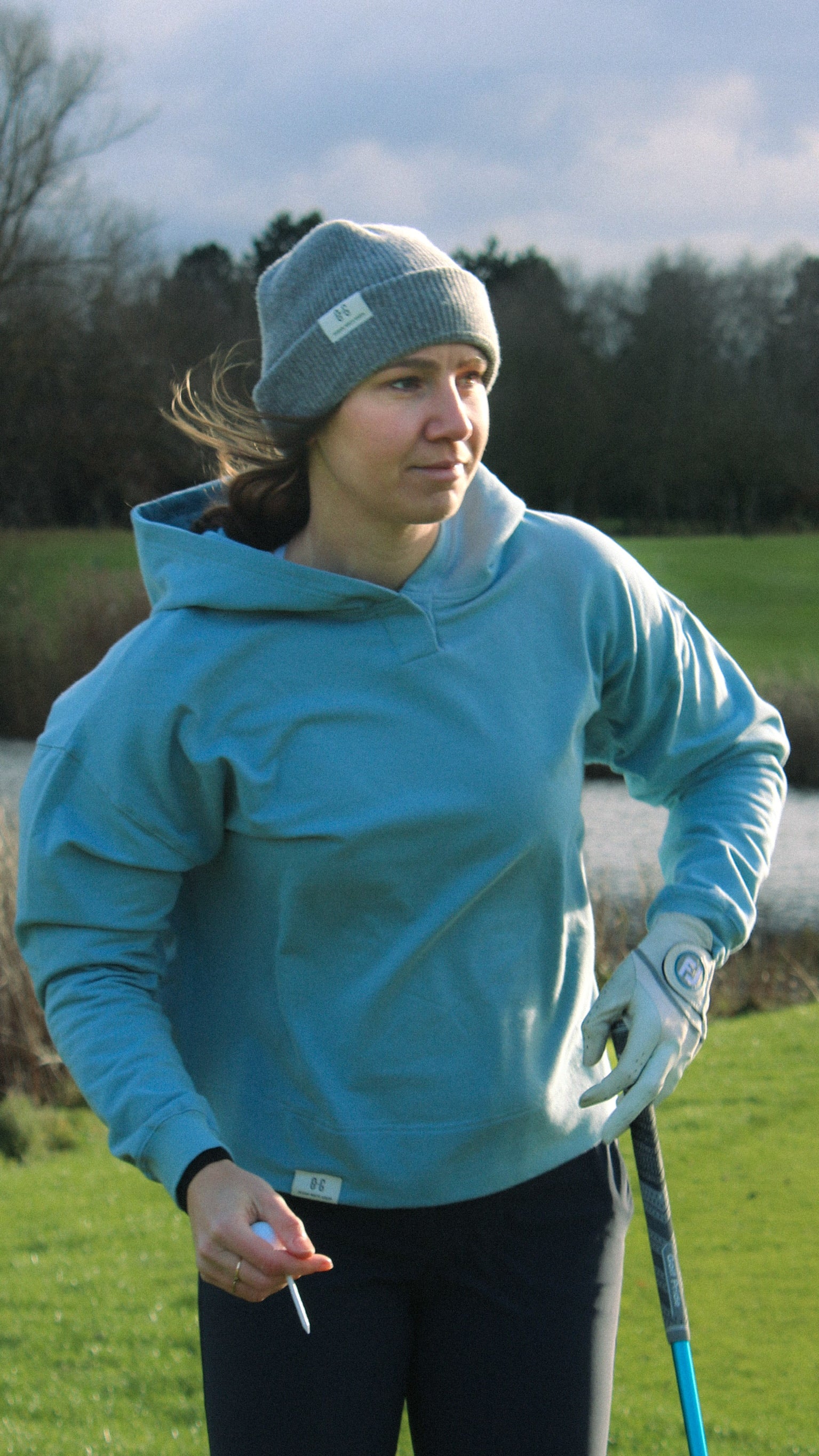 Ocean Meets Green Cloud beanie in grey, fine rib, made from merino wool, worn by a female golfer on the tee