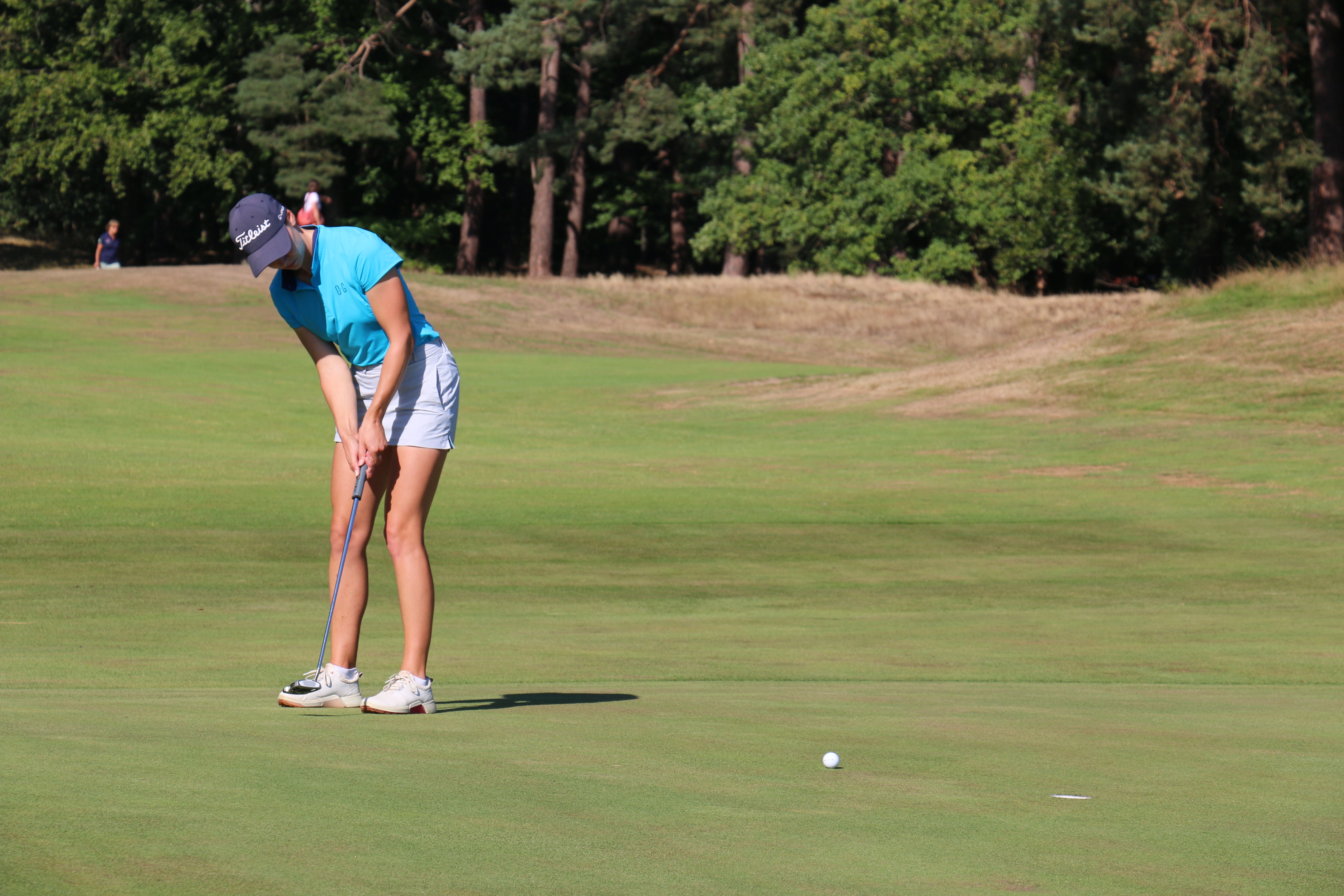 Image of female golfer wearing the Ocean Meets Green TIDE skirt in grey and the MOANA poloshirt in light blue