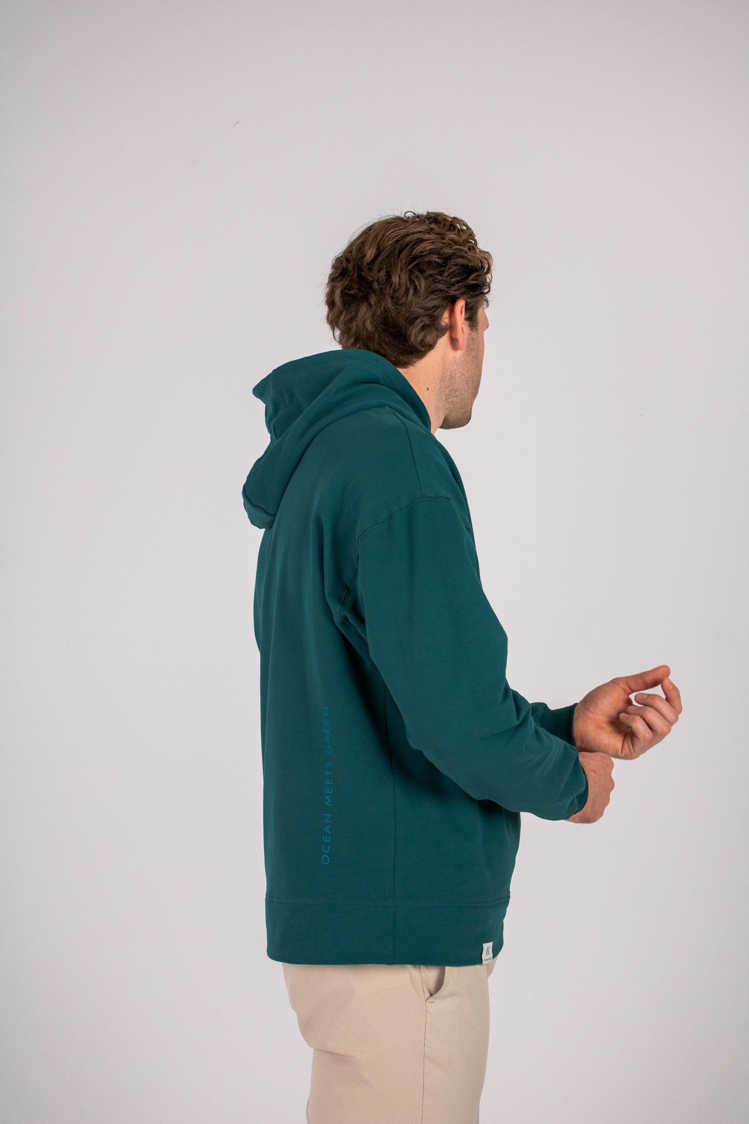 Full body image of Ocean Meets Green men's golf hoodie Wave in pine, showing the logo