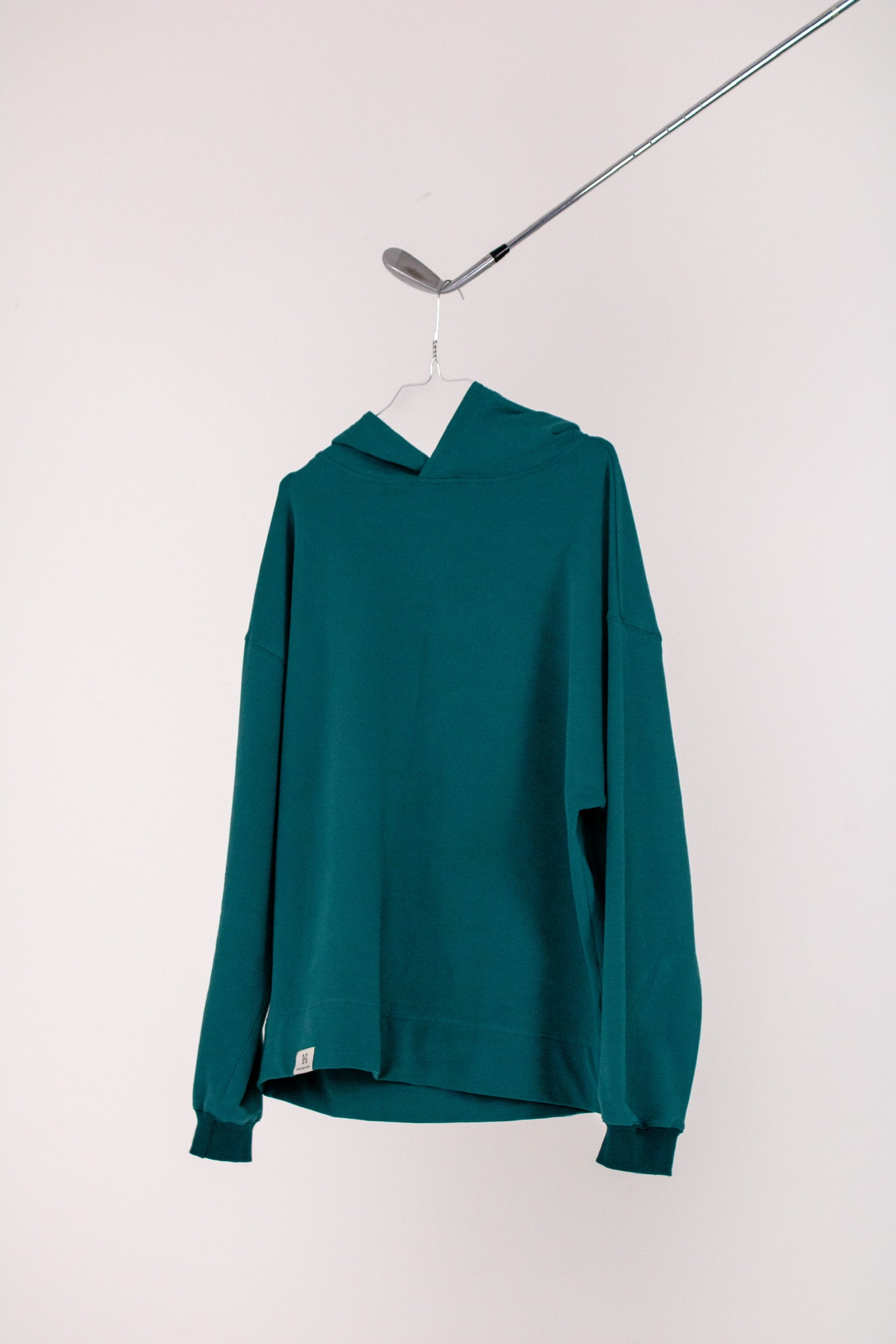 Image of Ocean Meets Green men's golf hoodie Wave in pine on a hanger