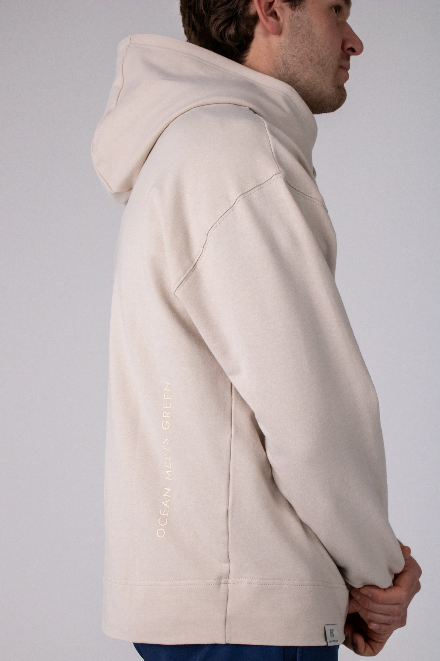 Full body image of Ocean Meets Green men's golf hoodie Wave in sand, showing the logo