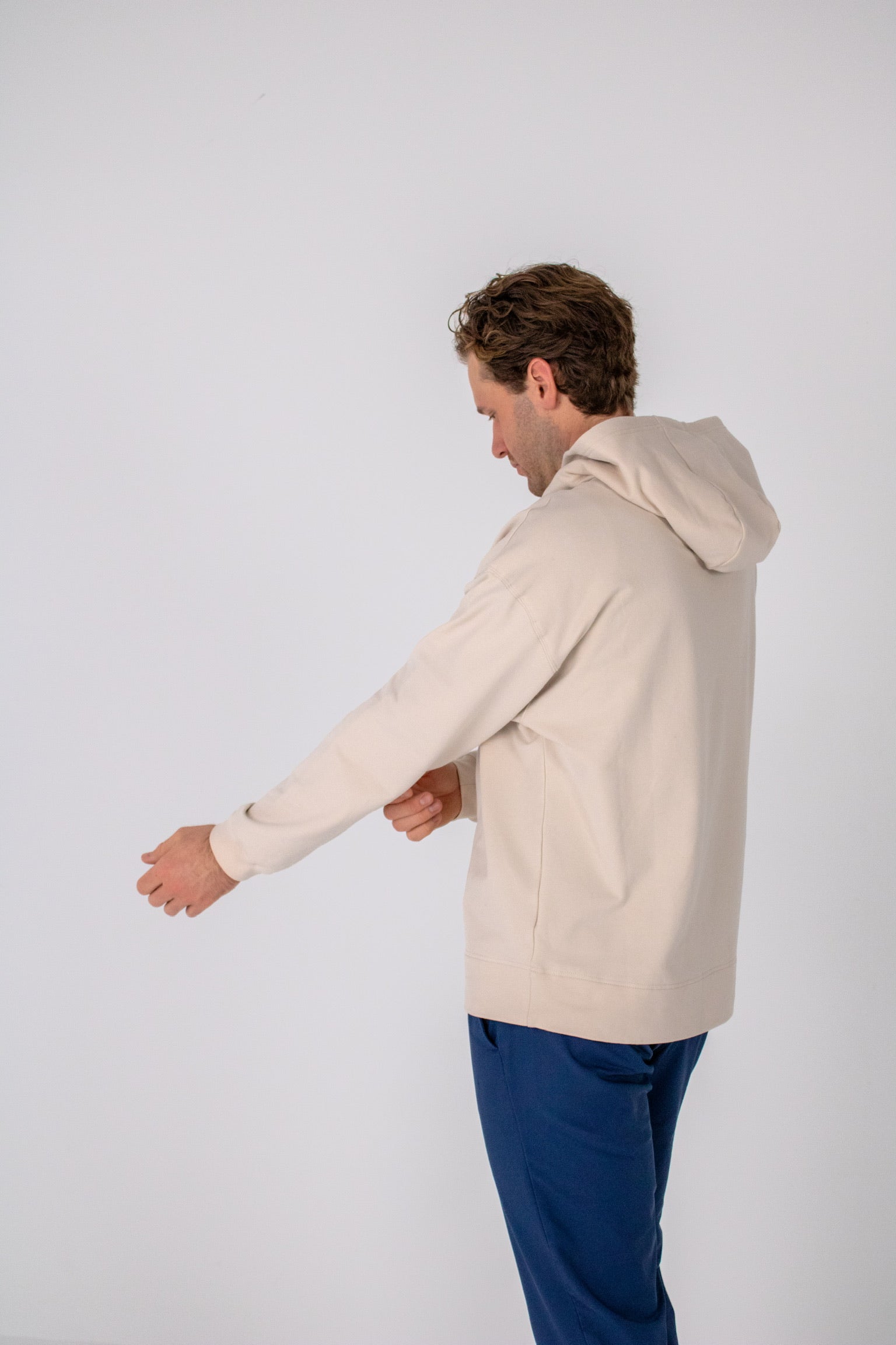 Full body image of Ocean Meets Green men's golf hoodie Wave in sand, pulling sleeves up