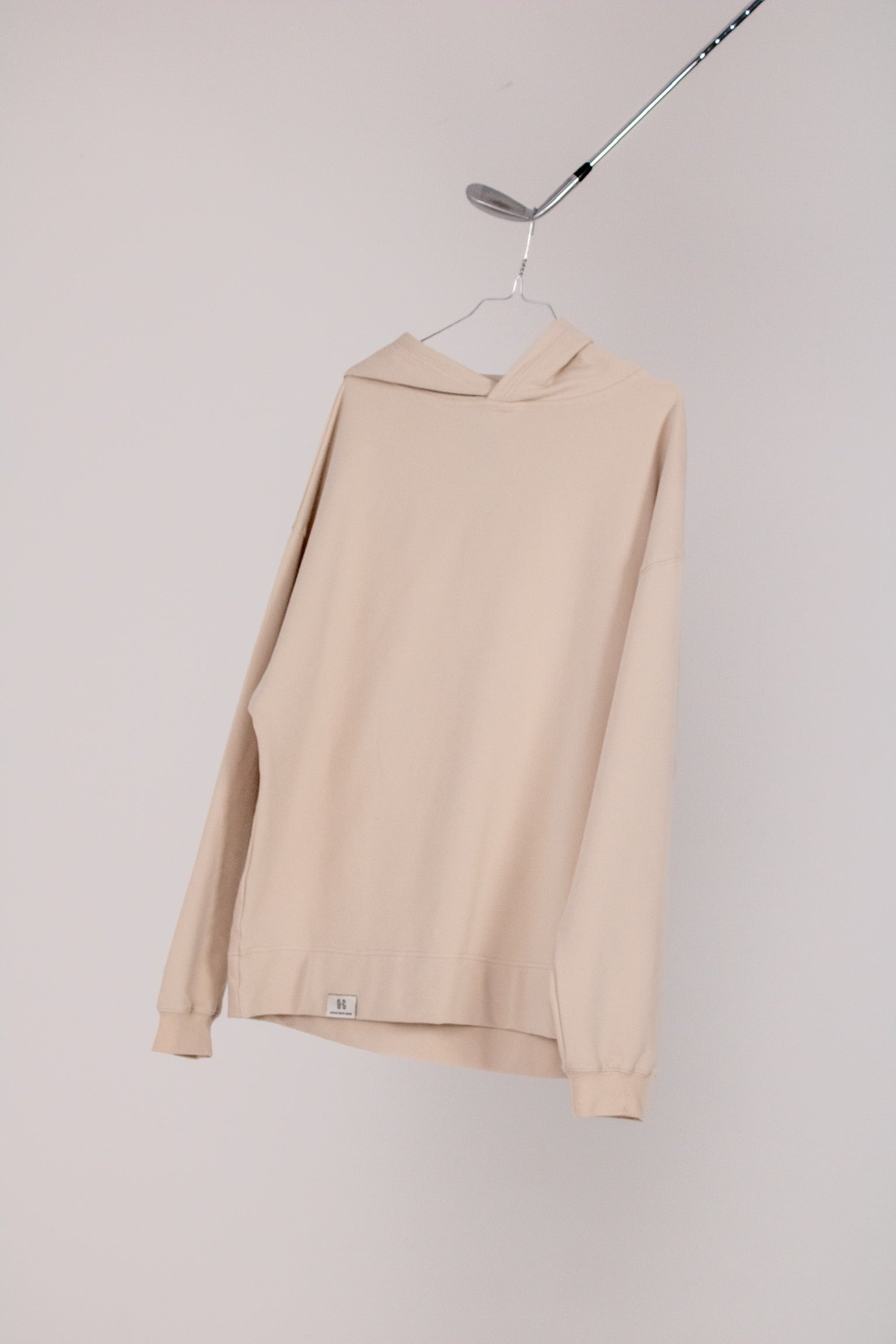 Image of Ocean Meets Green men's golf hoodie Wave in sand on a hanger