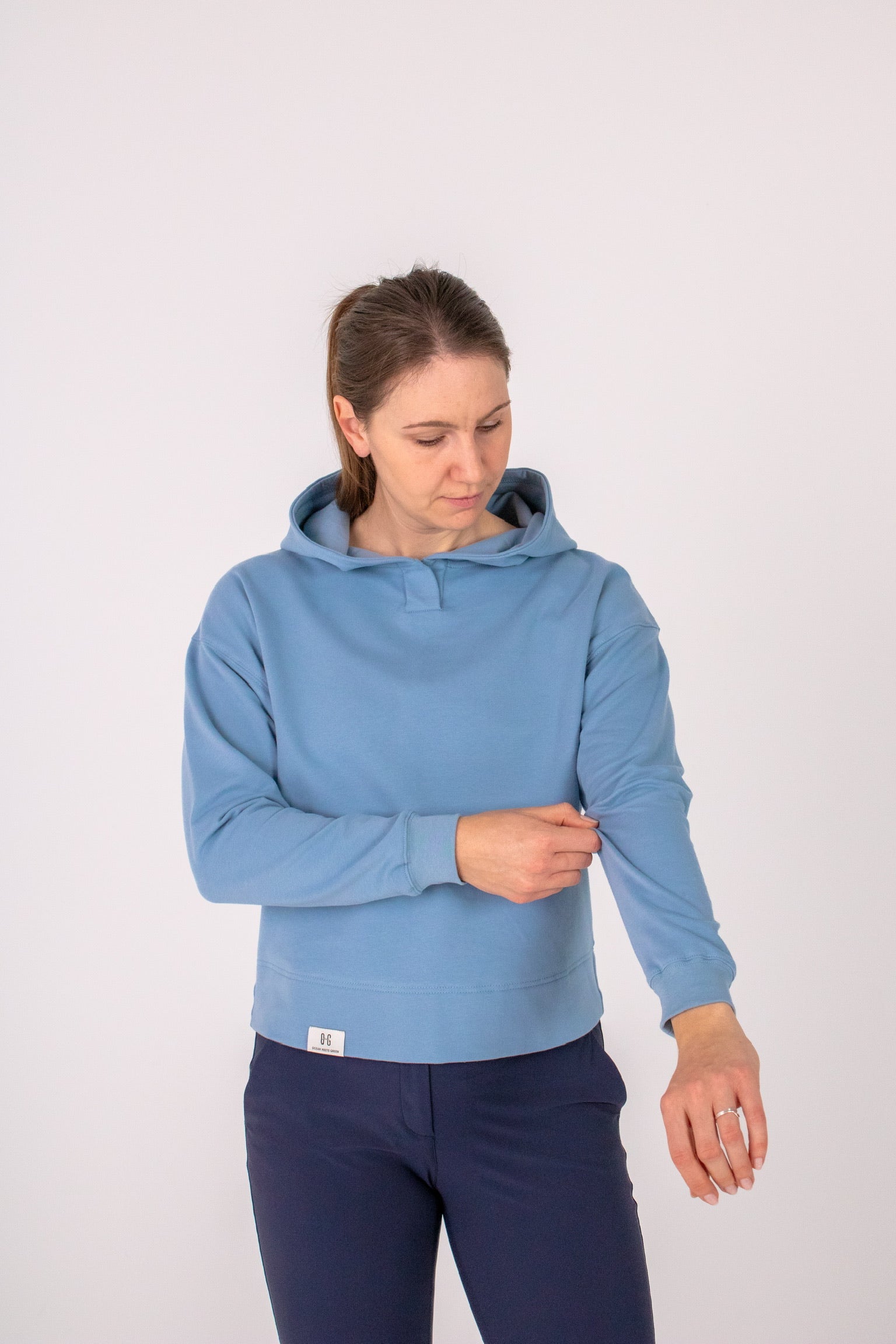 Fullbody image of Ocean Meets Green women's golf hoodie Flow in ice, pulling sleeve up