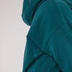 Closeup image of Ocean Meets Green women's golf hoodie Flow in pine, showing the logo