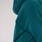 Closeup image of Ocean Meets Green women's golf hoodie Flow in pine, showing the logo
