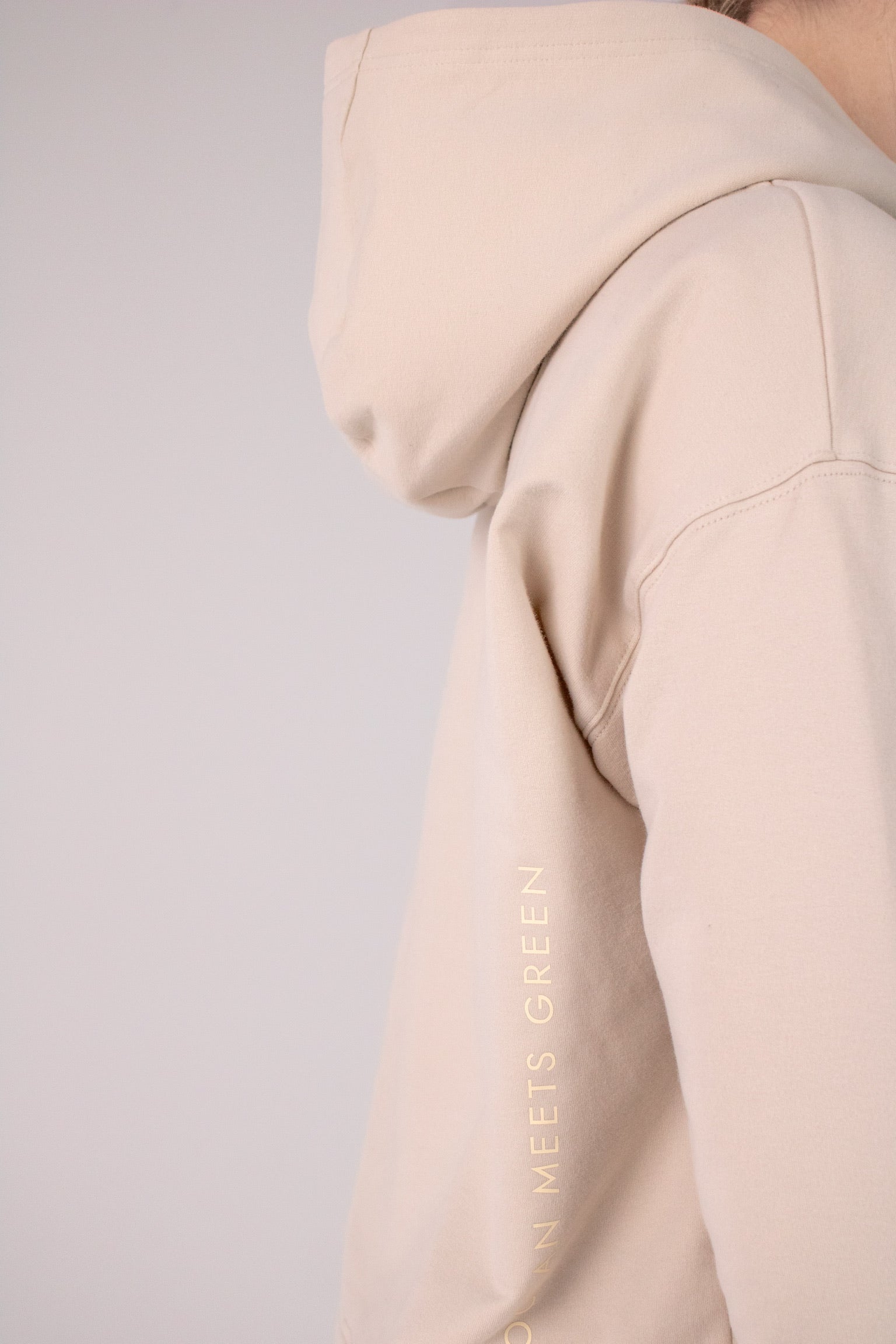 Closeup image of the logo on Ocean Meets Green women's golf hoodie Flow in sand