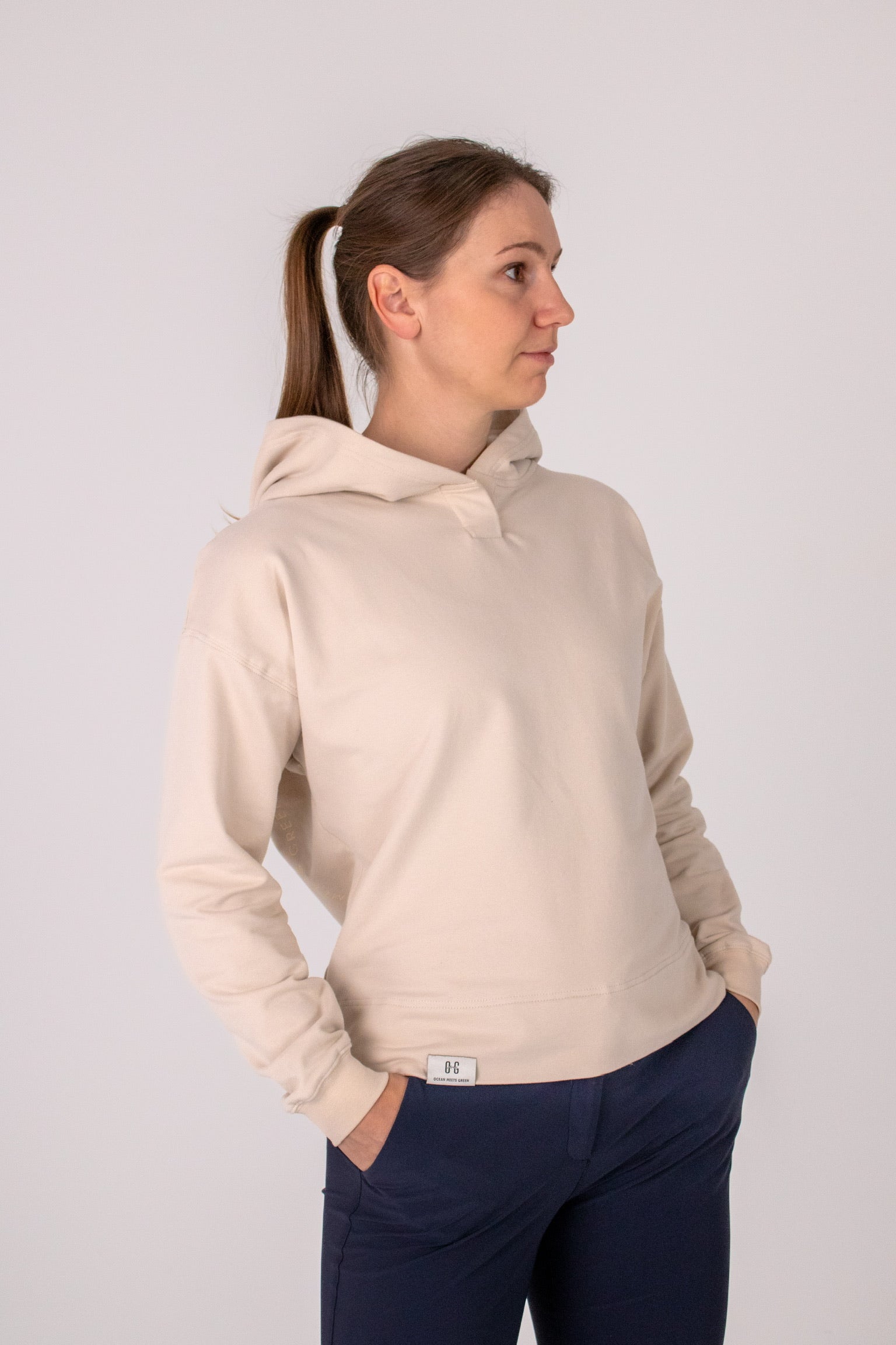 Fullbody image of Ocean Meets Green women's golf hoodie Flow in sand