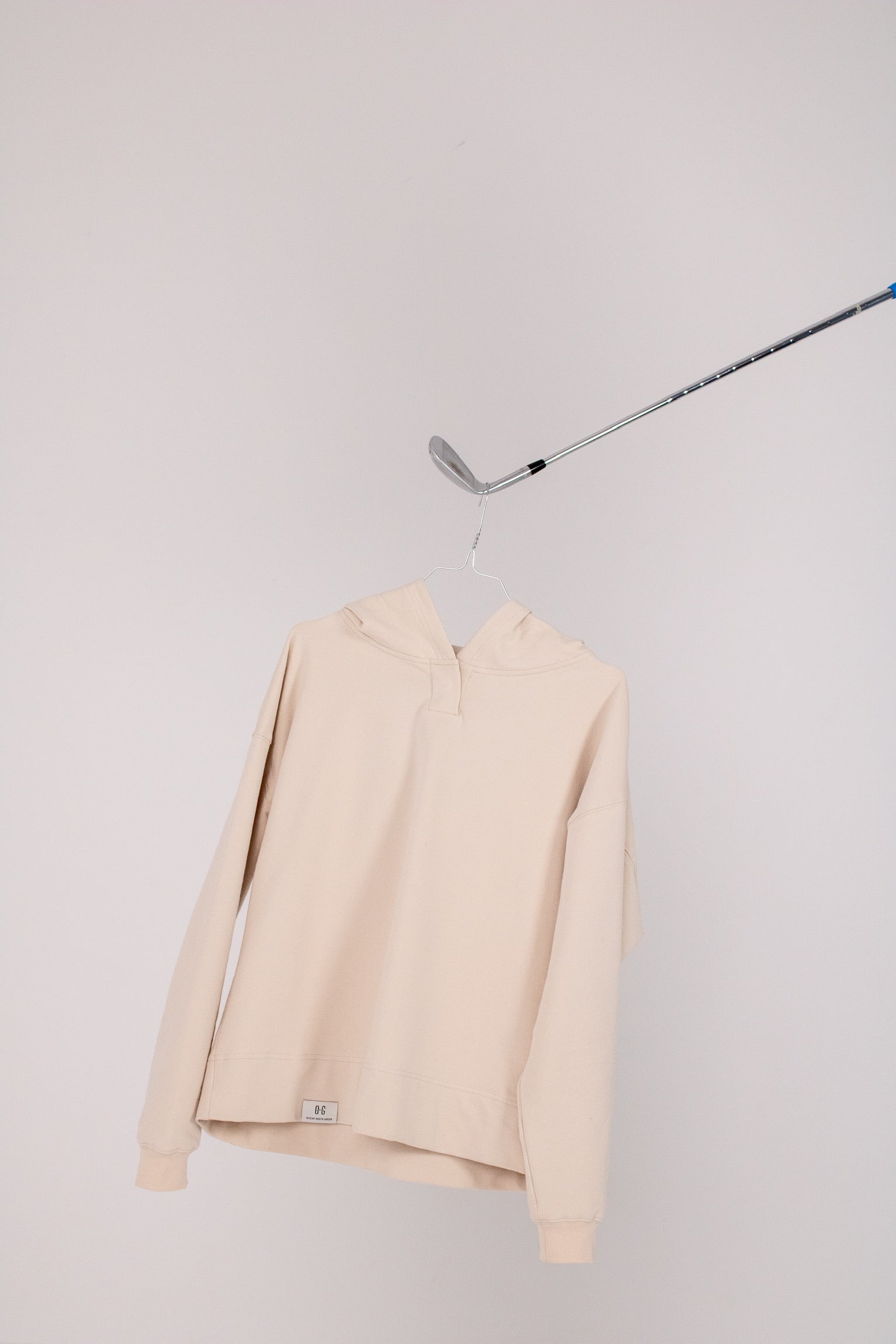 Image of Ocean Meets Green women's golf hoodie Flow in sand on a hanger