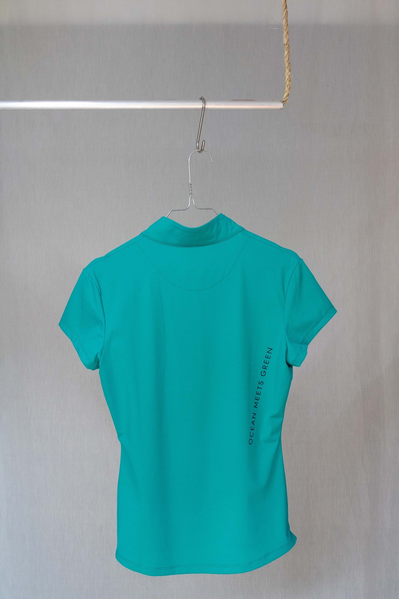 Image of Ocean Meets Green women's golf polo Moana in green on a hanger back view