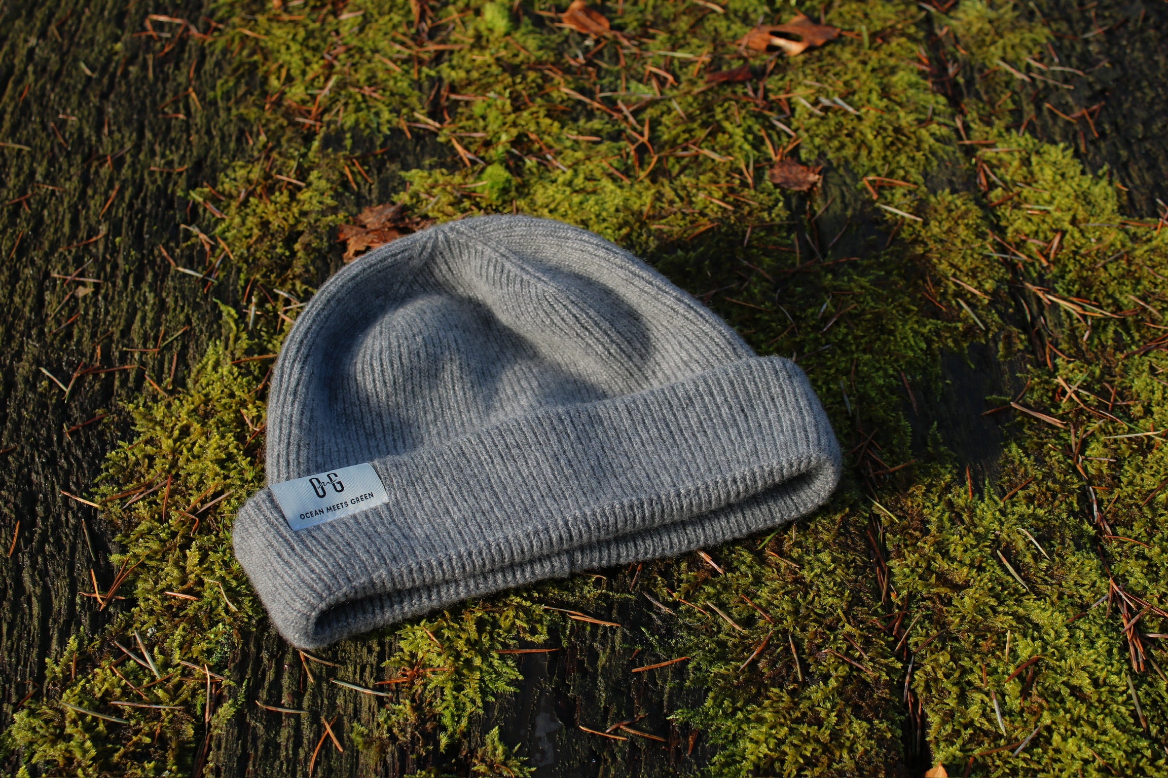 Closeup of the white logo label on the Ocean Meets Green Cloud beanie in grey, fine rib, made from merino wool