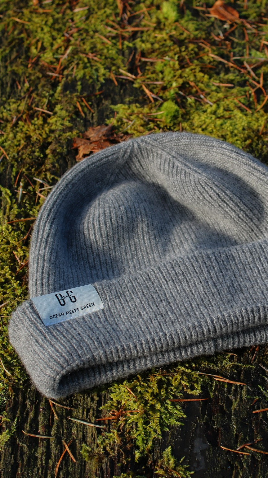 Closeup of the white logo label on the Ocean Meets Green Cloud beanie in grey, fine rib, made from merino wool