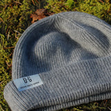 Closeup of the white logo label on the Ocean Meets Green Cloud beanie in grey, fine rib, made from merino wool