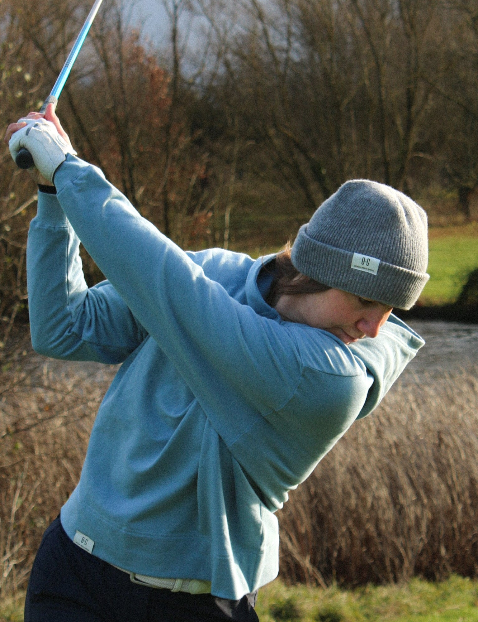 Ocean Meets Green Cloud beanie in grey, fine rib, made from merino wool, worn by a female golfer hitting a teeshot