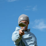 Ocean Meets Green Cloud beanie in grey, made from merino wool, worn by a male golfer pointing a club