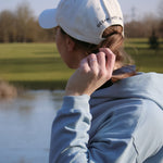 Ocean Meets Green Horizon cap in white with navy stitched logo, made from organic cotton, worn by a female golfer