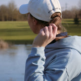 Ocean Meets Green Horizon cap in white with navy stitched logo, made from organic cotton, worn by a female golfer