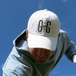 Ocean Meets Green Horizon cap in white with navy stitched logo, made from organic cotton, worn by a male golfer