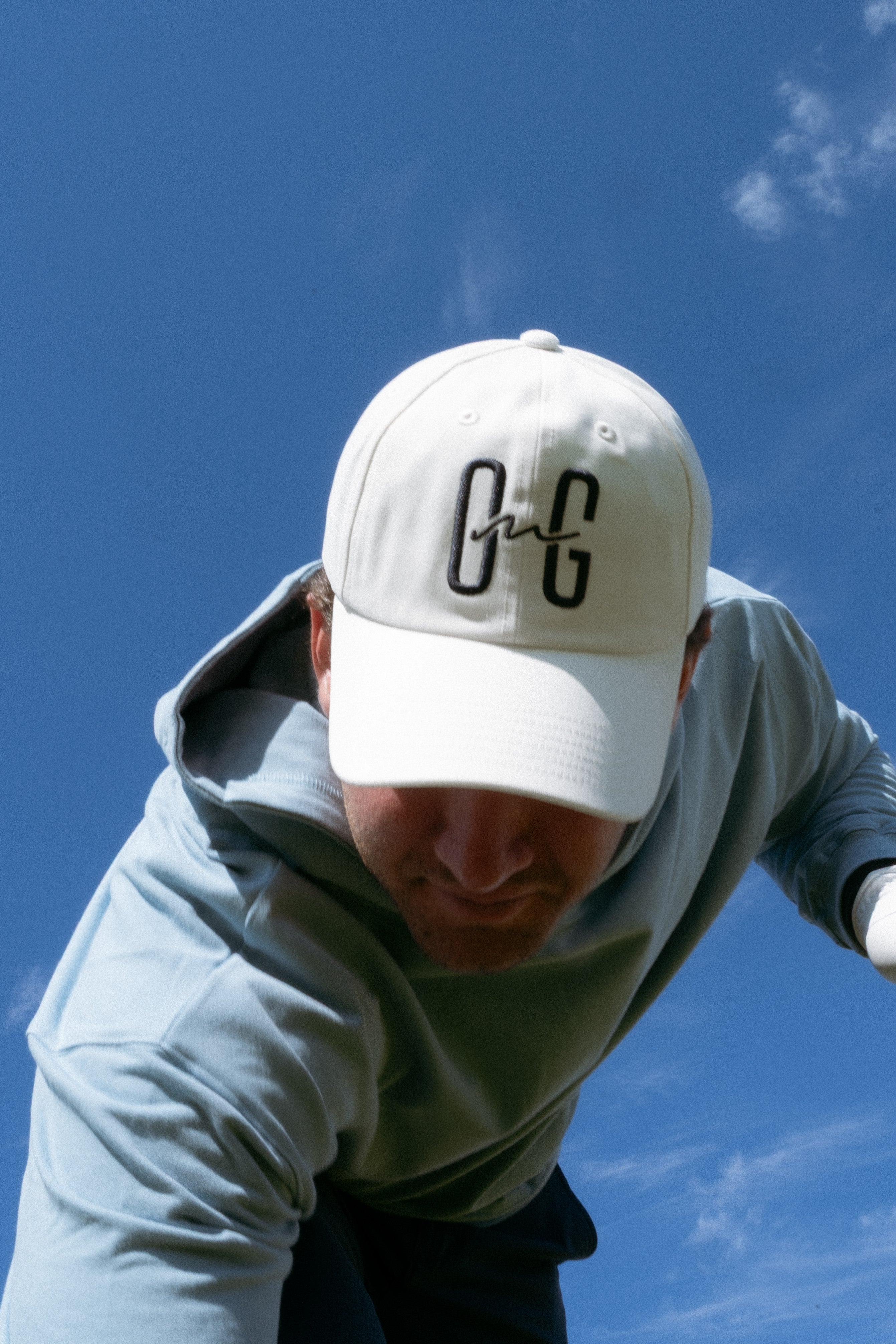 Ocean Meets Green Horizon cap in white with navy stitched logo, made from organic cotton, worn by a male golfer