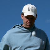 Ocean Meets Green Horizon cap in white with navy stitched logo, made from organic cotton, worn by a male golfer