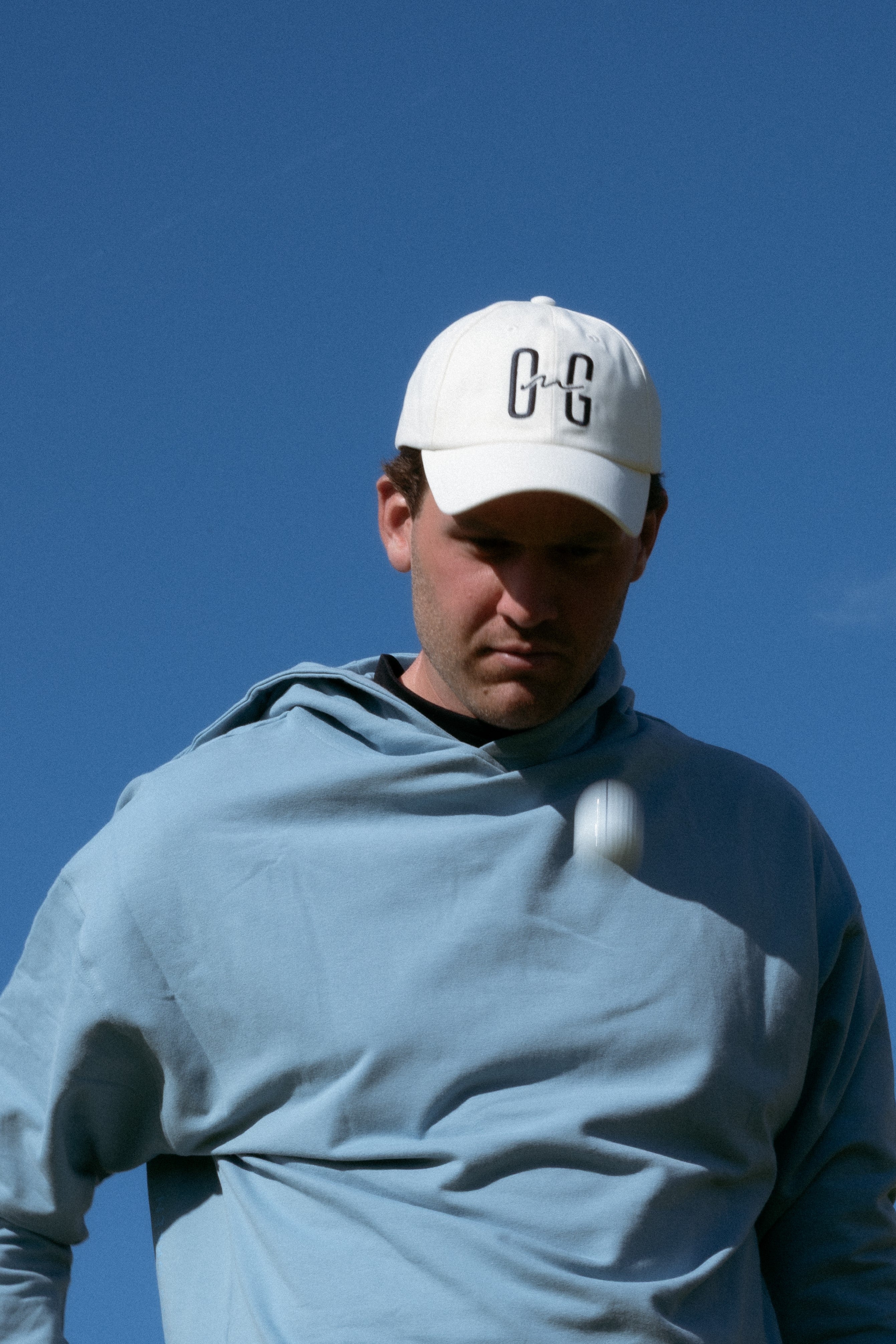 Ocean Meets Green Horizon cap in white with navy stitched logo, made from organic cotton, worn by a male golfer