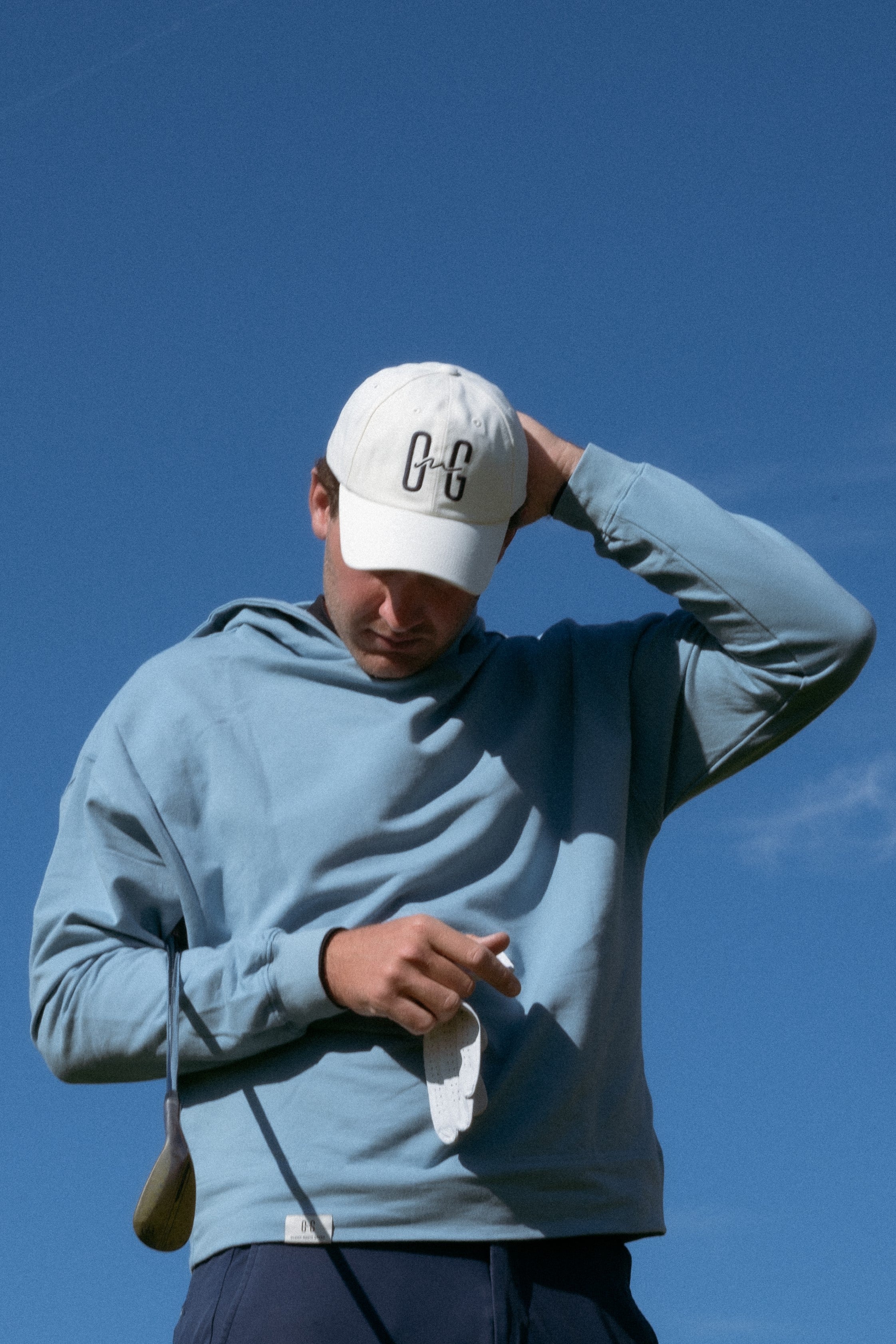 Ocean Meets Green Horizon cap in white with navy stitched logo, made from organic cotton, worn by a male golfer