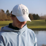 Ocean Meets Green Horizon cap in white with navy stitched logo, made from organic cotton, worn by a female golfer