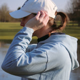 Ocean Meets Green Horizon cap in white with navy stitched logo, made from organic cotton, worn by a female golfer