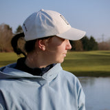 Ocean Meets Green Horizon cap in white with navy stitched logo, made from organic cotton, worn by a female golfer