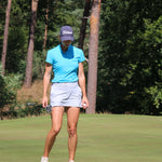 Image of female golfer wearing the Ocean Meets Green TIDE skirt in grey and the MOANA poloshirt in light blue