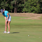 Image of female golfer wearing the Ocean Meets Green TIDE skirt in grey and the MOANA poloshirt in light blue