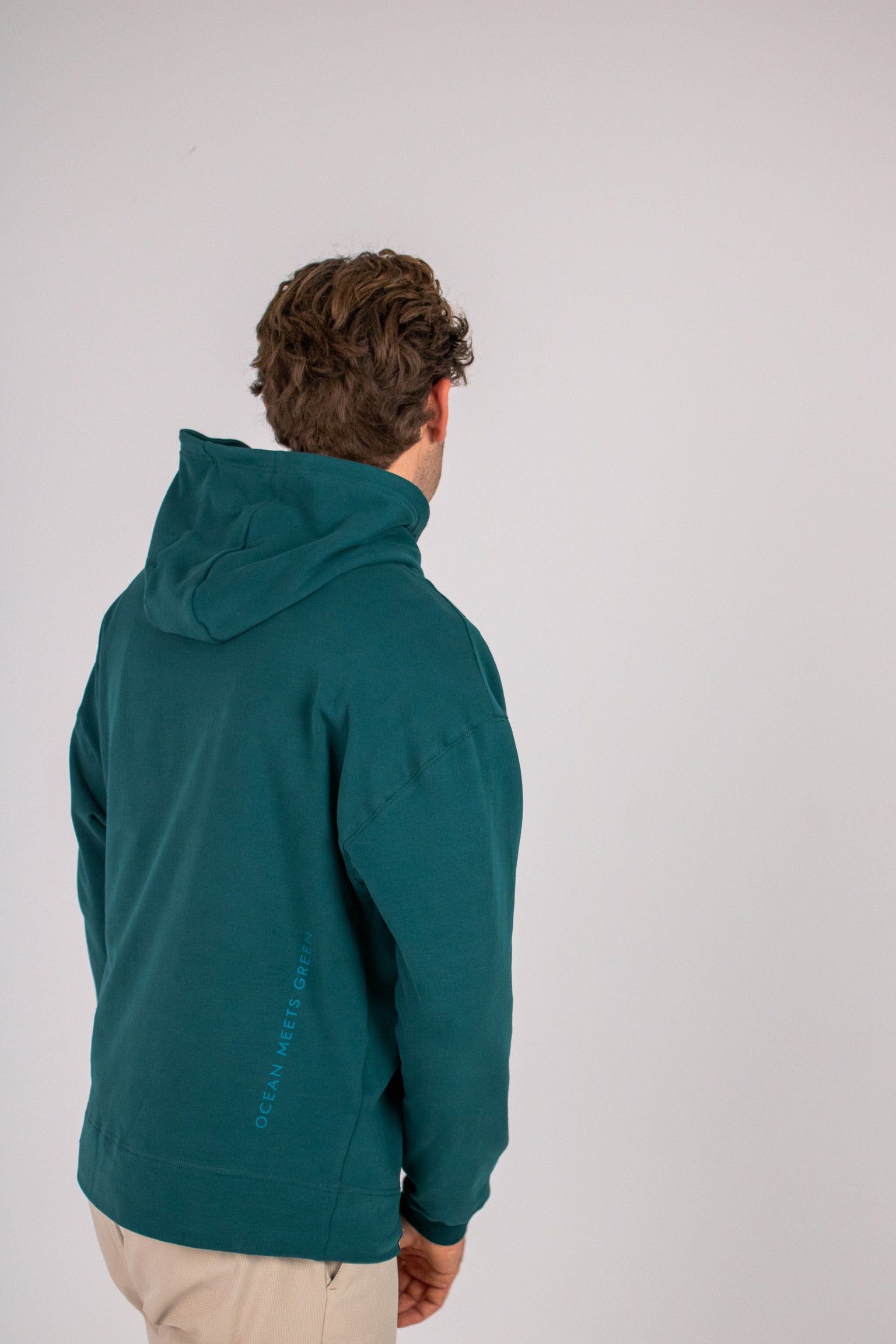 Full body image of Ocean Meets Green men's golf hoodie Wave in pine, showing the back