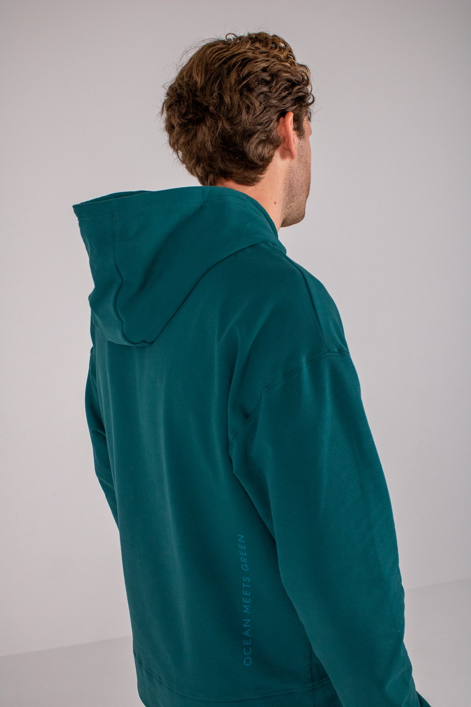 Full body image of Ocean Meets Green men's golf hoodie Wave in pine, showing the back
