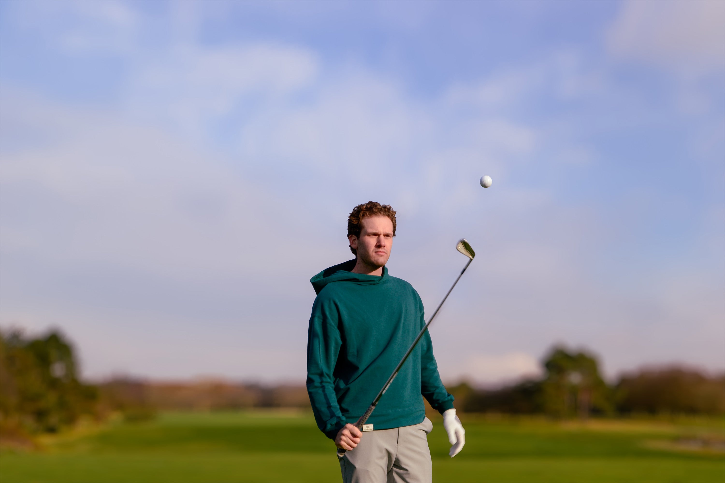 Image of Ocean Meets Green men's golf hoodie Wave in pine worn by Yannic on the course