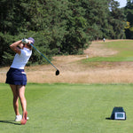 Image of female golfer wearing the Ocean Meets Green TIDE skirt in navy and the MOANA poloshirt in white