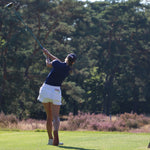 Image of woman wearing the Ocean Meets Green TIDE skirt in white and the MOANA poloshirt in navy