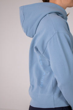 Image of Ocean Meets Green women's golf hoodie Flow in ice, showing the logo