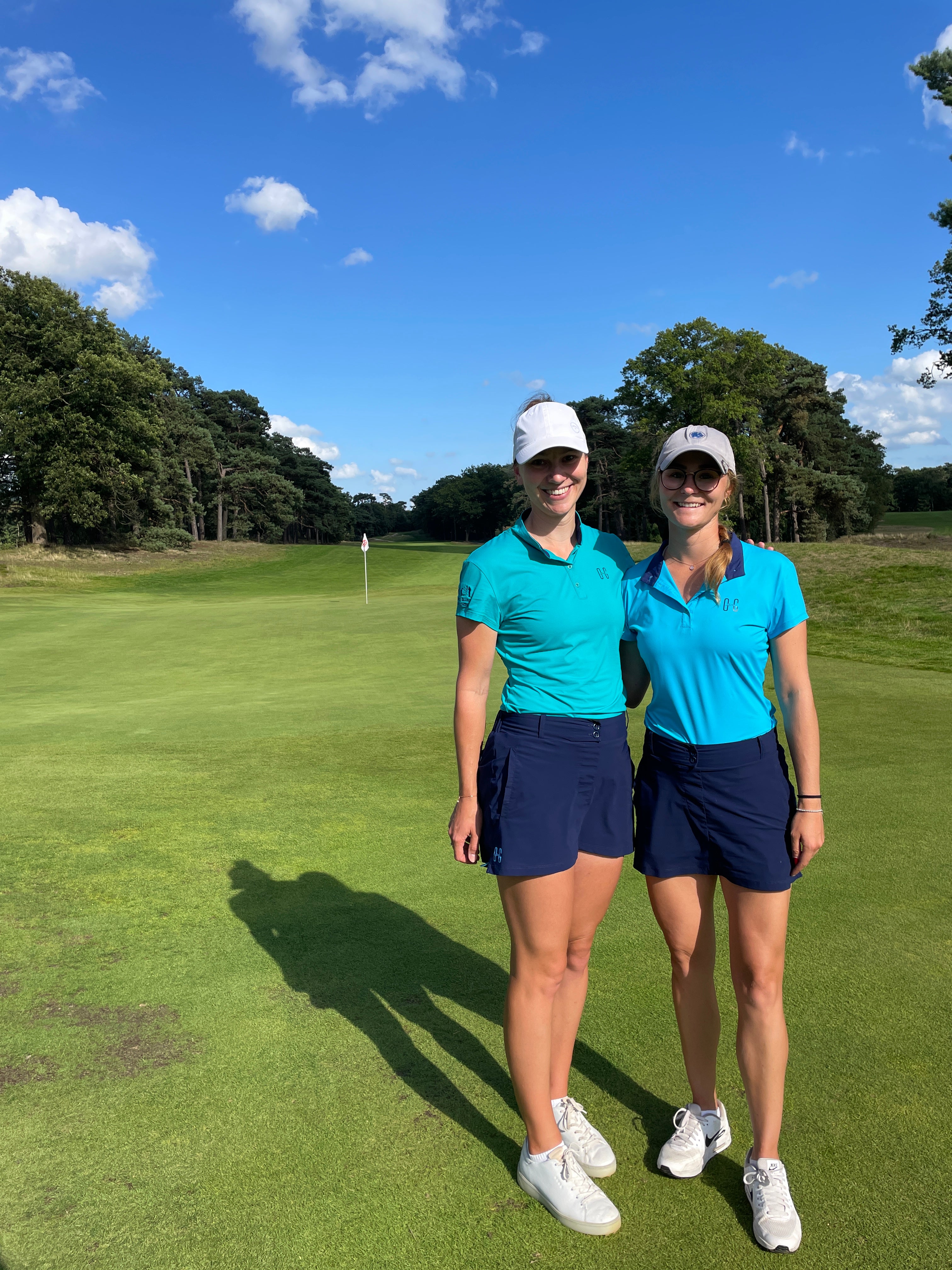 Image of two women wearing Ocean Meets Green outfits: Moana golf polo in light blue and Tide skirt in navy + Moana golf polo in green and Tide skirt in navy