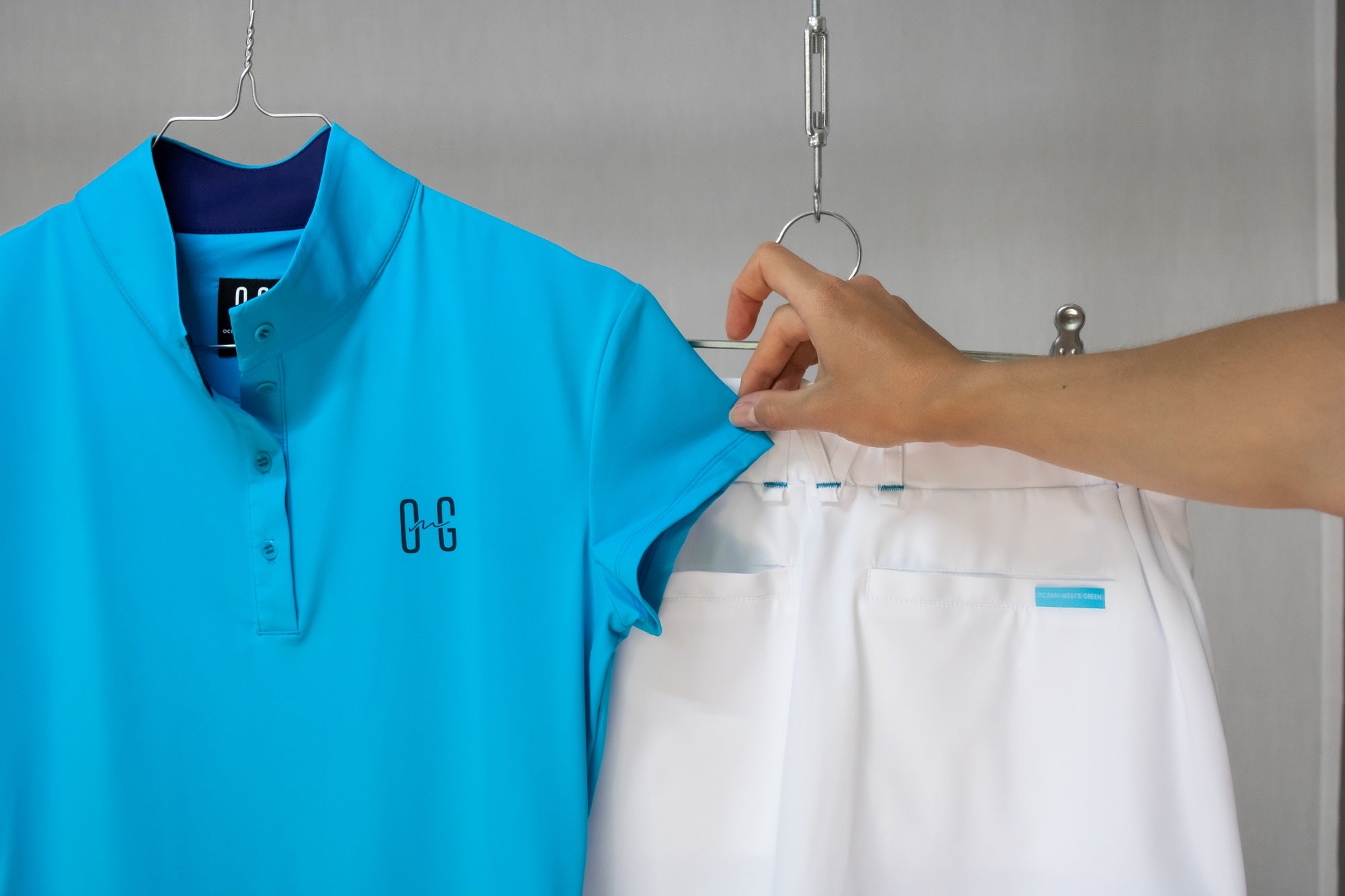 Image of Ocean Meets Green women's golf polo Moana in light blue and golf skirt Tide in white on a hanger