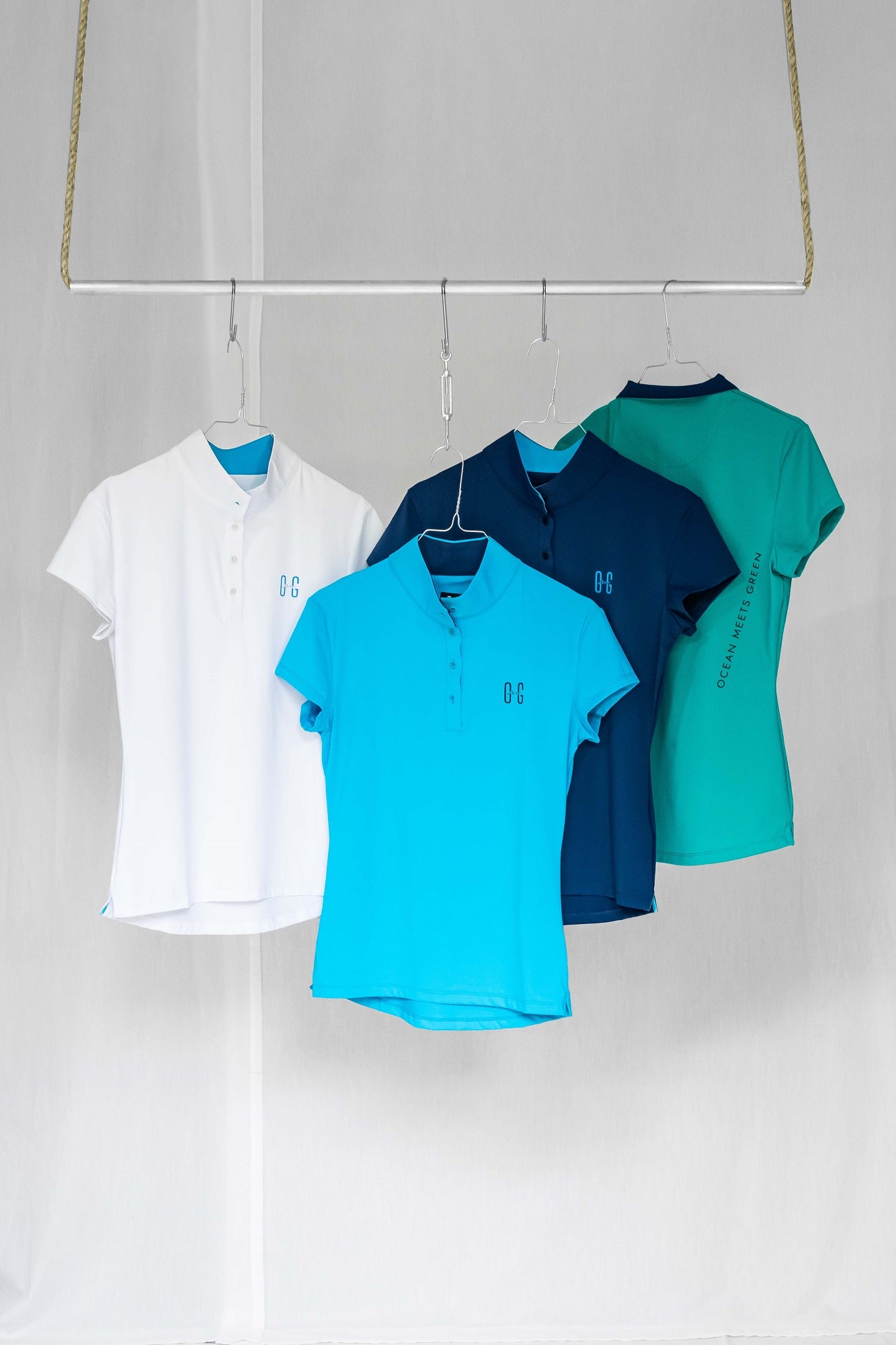 Image of Ocean Meets Green women's golf polos Moana in colors white, light blue, green and navy hangers