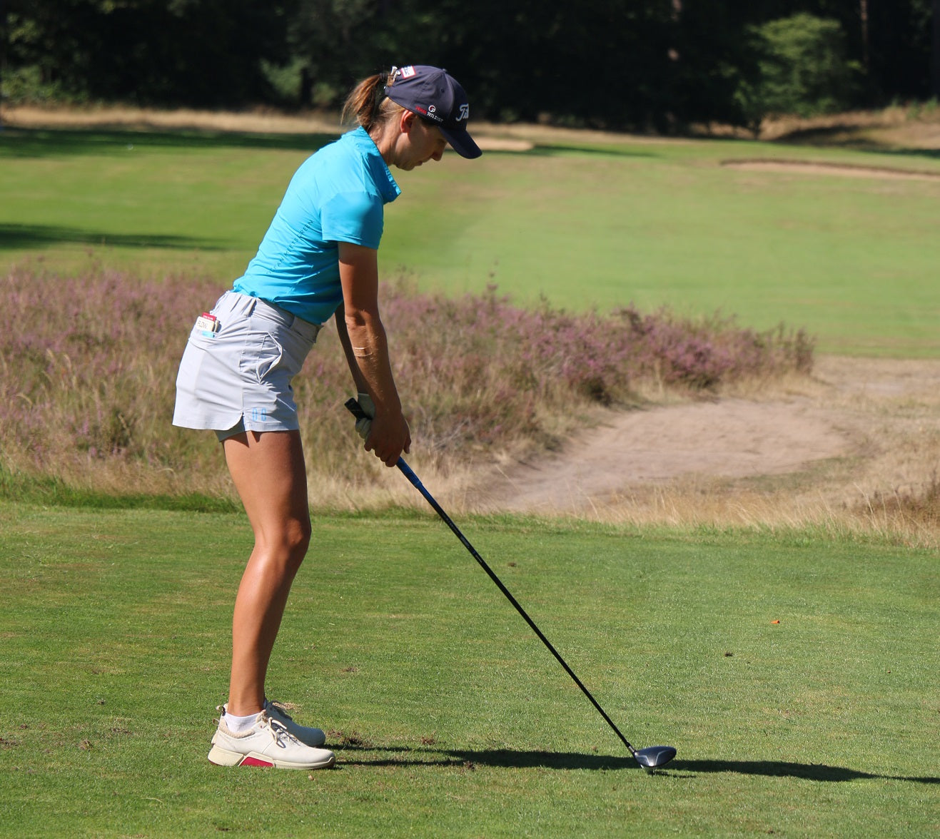 Image of female golfer wearing the Ocean Meets Green TIDE skirt in grey and the MOANA poloshirt in light blue