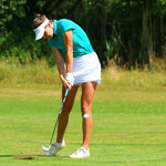 Image of female golfer wearing the Ocean Meets Green TIDE skirt in white and the MOANA poloshirt in green