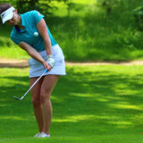 Image of female golfer wearing the Ocean Meets Green TIDE skirt in white and the MOANA poloshirt in green
