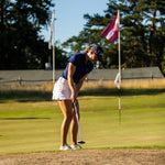 Image of woman wearing the Ocean Meets Green TIDE skirt in white and the MOANA poloshirt in navy