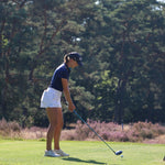 Image of woman wearing the Ocean Meets Green TIDE skirt in white and the MOANA poloshirt in navy