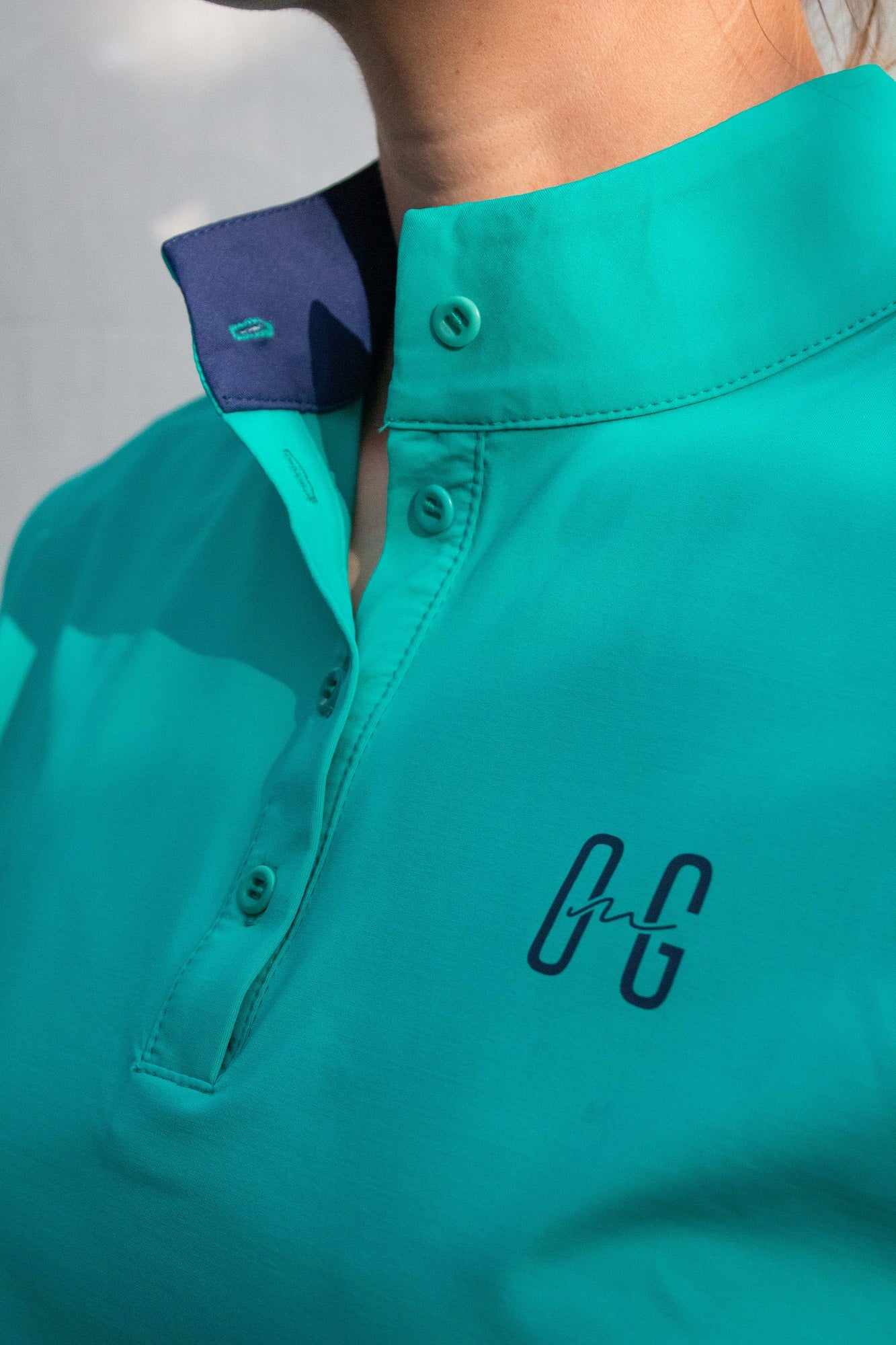 Image of Ocean Meets Green women's golf polo Moana in green, showing the standup collar and front logo