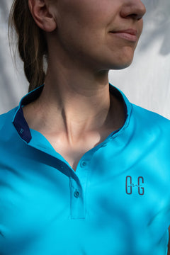 Image of Ocean Meets Green women's golf polo Moana in light blue, showing the standup collar and front logo