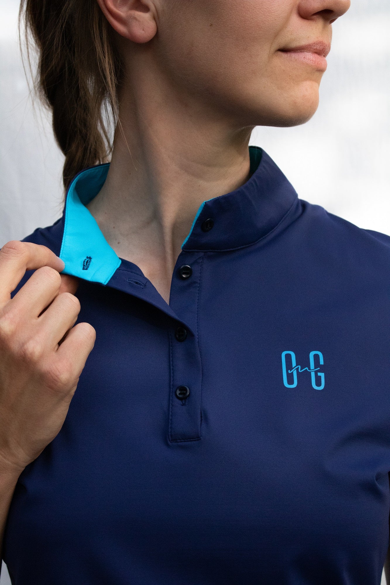 Image of Ocean Meets Green women's golf polo Moana in navy, showing the standup collar and front logo