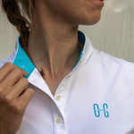 Image of Ocean Meets Green women's golf polo Moana in white, showing the standup collar and front logo